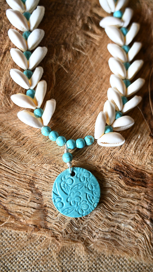 Handcrafted Ceramic necklace with Plumeria design on the pendant, glazed with Aqua glaze, hand-strung with Cowrie Shells and Turquoise Beads necklace