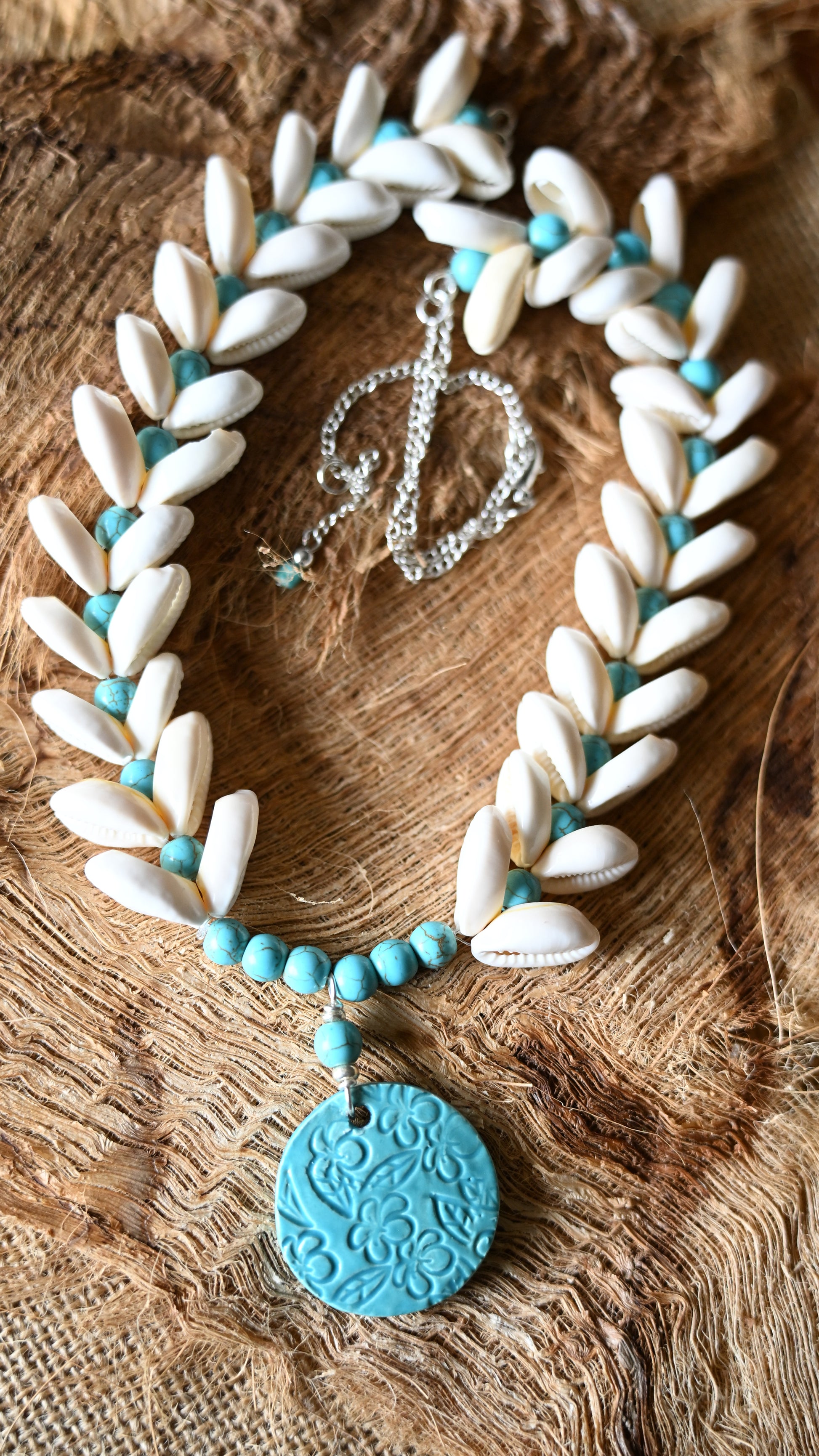 Handcrafted Ceramic necklace with Plumeria design on the pendant, glazed with Aqua glaze, hand-strung with Cowrie Shells and Turquoise Beads necklace.